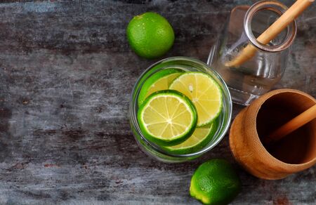 Top view lemons and lime slices for detox water on gray wooden background, a drinking water for healthy diet and skin careの写真素材