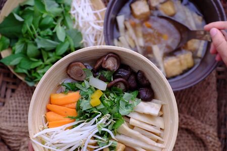 Woman hand prepare food by spoon from soup pot for breakfast, bun mang bowl, bamboo shoot noodles...