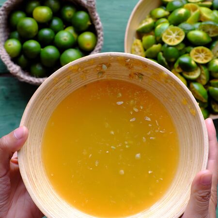 Top view people hand hold kumquat juice that squeezed out of fruits, this sour fruit rich vitamin c,...