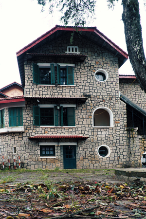 DA LAT, VIET NAM- AUG 3, 2019: Amazing French architecture of ancient stone house with green wooden window and door, exterior stone wall of villa link to historyのeditorial素材