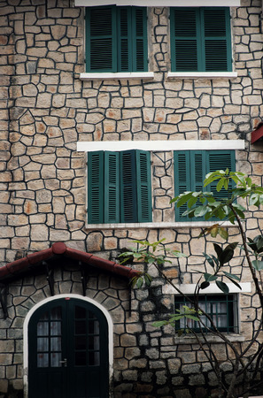 Amazing French architecture of ancient stone house with green wooden window and door, exterior stone wall of villa link to history, Da Lat, Viet Namのeditorial素材