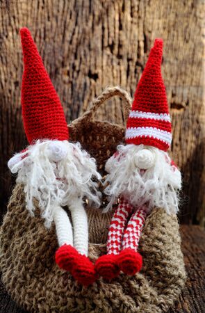 Concept celebration winter seasonal with two red Christmas gnome ornament relax together, handmade stuffed toy crochet from yarn wear long hat, white beard so cute for decoration dec festival seasonの写真素材