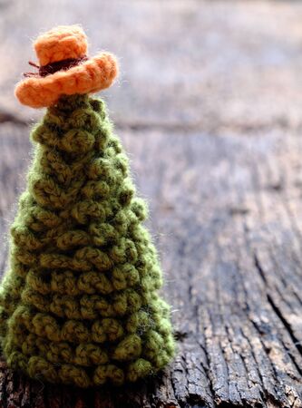 handmade ornament for winter season at wintertime, crochet Christmas tree from green yarn wear colorful hat on dark background, amazing craft gift for home decorの写真素材