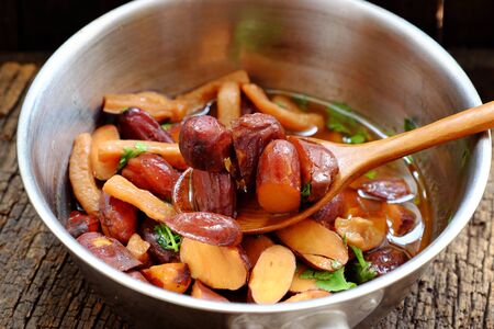 Close up pot of jackfruit seeds cook with sauce and spice and raw material on dark wooden background, Vietnamese homemade vegan food from nut for vegetarian meal that delicious and nutritionの写真素材