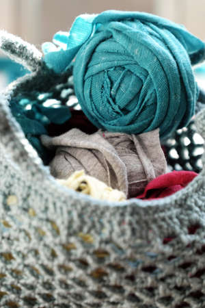 Close up ball of yarn in bag from recycle old t shirt on white background, fun leisure with homemade reuse by cut clothes in yarns, colorful scene in sunlight morning  の写真素材