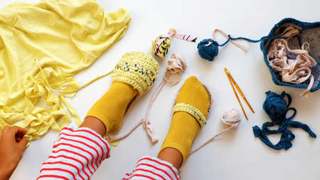 Top view leisure activity to make handmade sandals from old T shirt, Vietnamese woman recycle by cut clothes to make yarn ball then crochet, human foot diy thongs on white backgroundの写真素材