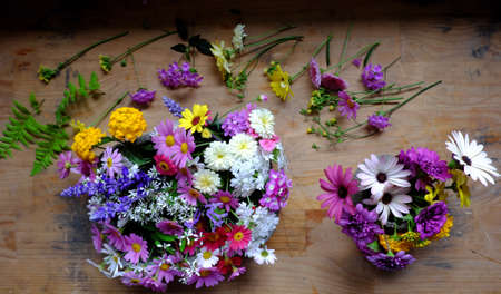 Beautiful colorful flower arrangement for decor inside home, variety tiny daisy just cut from home garden to make wonderful space in spring time, vase of flowers ready to decoration on woodenの写真素材