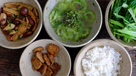 Frugal meal with vegetarian food, jackfruit and tofu skin cook with sauce, boiled vegetable, bitter melon soup, top view healthy tray for food on white for lunchの写真素材