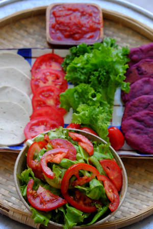 Amazing colorful raw material food for vegan hamburger from violet sweet potato with tomato sauce, salad, cucumber, healthy food for breakfast that rich starch, fiberの写真素材
