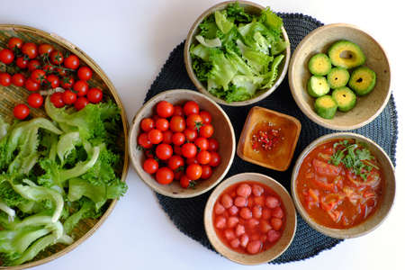 Vietnamese healthy food with vegan ingredient in green, red, salad mix with tomato sauce, strawberry, avocado, nutrition eating for detox, diet menu in rich vitamin on white backgroundの写真素材
