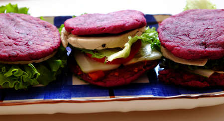 Amazing colorful raw material food for vegan hamburger from violet sweet potato with tomato sauce, salad, cucumber, healthy food for breakfast that rich starch, fiberの写真素材