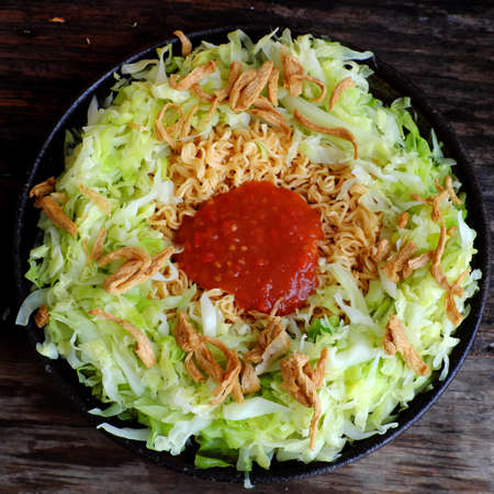 Quick and cheap vegan food for breakfast from instant noodles, fried with cabbage and tomato sauceの写真素材
