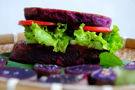 Amazing vegan hamburger from violet sweet potato with tomato, salad, healthy food for breakfast that rich starch, fiberの写真素材