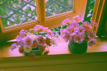 Two beautiful pink flower vase with many tiny daisy blossom on wooden window frame of house to decor home in springtimeの写真素材