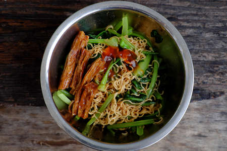 Quick and cheap vegan food for breakfast from instant noodles, fried with kale and tomato sauceの写真素材