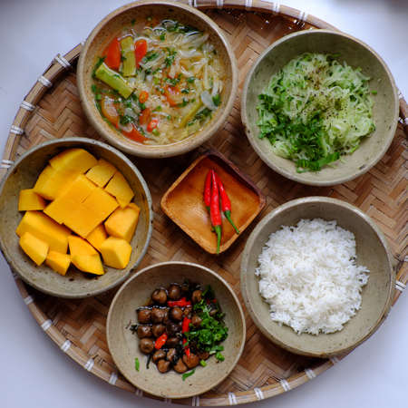Top view Vietnamese vegan daily family meal for lunch, tray of rice dish with fried chayote, sour soup, straw mushrooms cook with sauce, vegetarian menu with non meat good for healthの写真素材