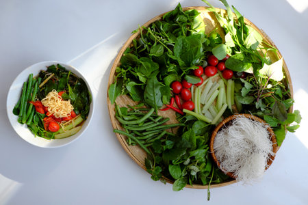 Top view Vietnamese vegan food for lunch meal, tomato soup bowl cook with ripe tamarind, colocasia gigantea and basil leaf, simple dish but delicious homemade eatingの写真素材