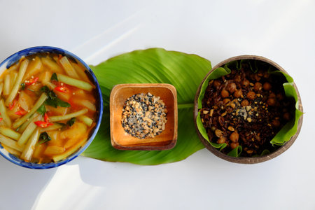 Vietnamese cuisine from red rice, delicious and nutrition rice dish for lunch, homemade food rich nutritious in coconut shell bowl with sesame salt on green leaf backgroundの写真素材