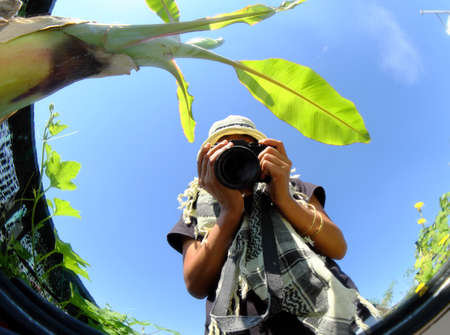 Amazing Vietnamese female photographer take photo by selfie via convex mirrors, woman sit on wooden...