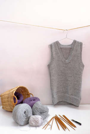 Handmade product to make gift for winter season, ball of yarn material for knit and man vest in grey hang on white background, handcraft with woolen clothes in cold season, Da Lat, Vietnamの写真素材