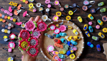 Top view Vietnamese woman hand hold handmade product, crochet hair pin in many shape and colorful, pretty handcraft gift accessories for beauty on black backgroundの写真素材