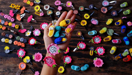 Top view Vietnamese woman hand hold handmade product, crochet hair pin in many shape and colorful, pretty handcraft gift accessories for beauty on black backgroundの写真素材