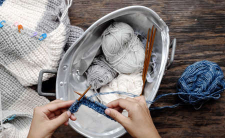 Top view, Vietnamese woman hands with ball of yarn to make winter present, female knitting woollen...
