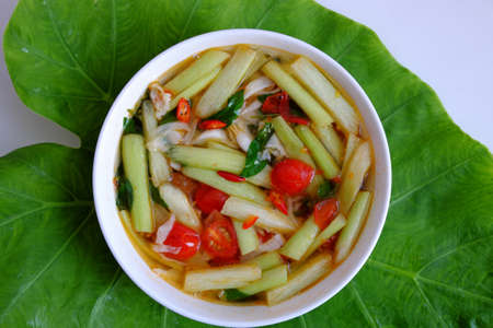 Top view Vietnamese vegan food for lunch meal, tomato soup bowl cook with ripe tamarind, colocasia gigantea and basil leaf, simple dish but delicious homemade eatingの写真素材