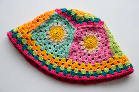 Top view handmade product to make spring present, colorful bucket hat with many piece link together, cute crochet hat from yarn on white backgroundの写真素材
