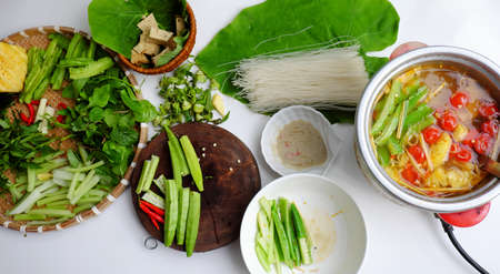 Top view Vietnamese vegan food, healthy eating from vegetal, green vegetables hot pot homemade from tomato, okra, dragon bean, herbal leaf, spinach, tofu skin, and dried noodlesの写真素材