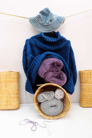 Handmade product for winter season gift, ball of yarn material to knit in bamboo basket, man blue sweater hang on white background, handcraft with woolen clothes in cold season, Da Lat, Vietnamの写真素材