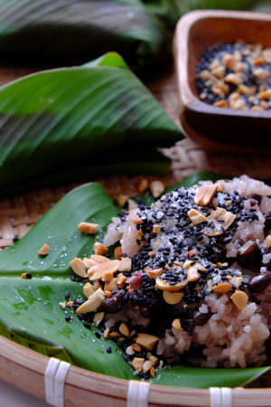 Top view Vietnamese homemade black bean sticky rice with sesame salt for cheap and quick breakfast in green leaf on bamboo basket on white backgroundの写真素材