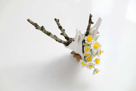 Daisy vase for home decor, flower pot diy by recycle face mask with white cement, crochet tiny white flower with yellow pistil and dry branch of tree on white backgroundの写真素材