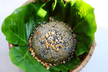 Top view Vietnamese homemade sticky rice with sesame salt for cheap and quick breakfast on green leaf in bamboo basket on white background with sunnyの写真素材