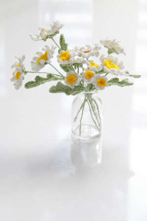 Amazing handmade flower pot for home decor, white petal daisy and yellow pistil crochet from yarn at leisure activities on white backgroundの写真素材