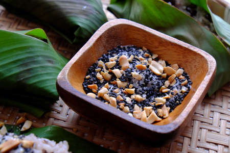 Top view Vietnamese homemade black bean sticky rice with sesame salt for cheap and quick breakfast in green leaf on bamboo basket on white backgroundの写真素材