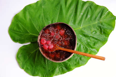 Top view red sugared strawberries in bowl that make from coconut shell on green leaf, red fresh Da Lat fruit for summer day, yummy foodの写真素材