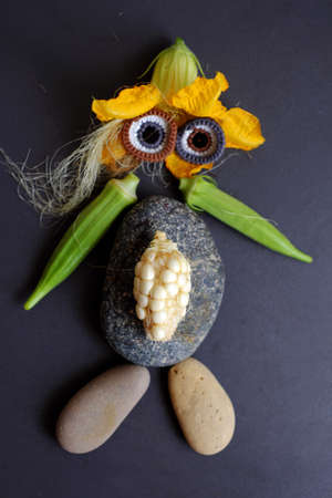 Funny face set up from food, agriculture product from rooftop garden, small corn, pumpkin flower, corn silk, okra fruit, pebble and eyes crochet from yarn make cute shapeの写真素材