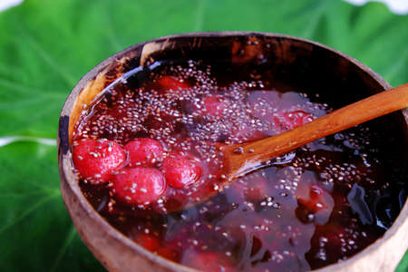 Top view red sugared strawberries in bowl that make from coconut shell on green leaf, red fresh Da...