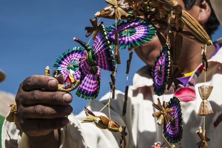 Uros Floating Islands, Titicaca, Peru - 30 July 2011: Unrecognizable man in national costume Indian Uros show the souvenir from reedのeditorial素材