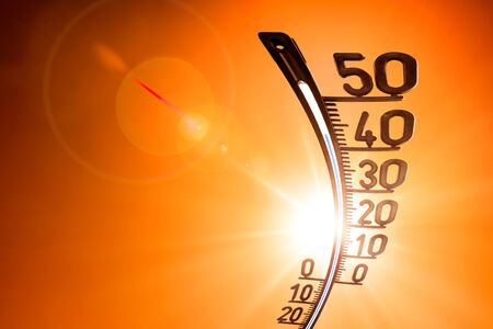 Glowing sun on orange sky with thermometer as a symbol for global warmingの写真素材