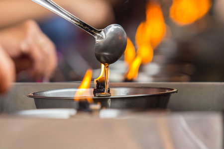 People fill oil to lantern for merit in the temple.の写真素材