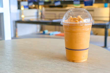 Thai milk tea spin with ice in plastic glass on wooden table.の写真素材
