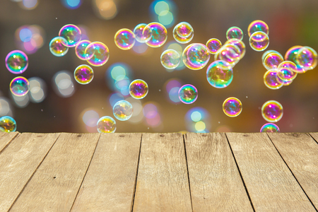 Empty wooden table or plank with bokeh of rainbow soap bubbles from the bubble blower on background for product display.の写真素材