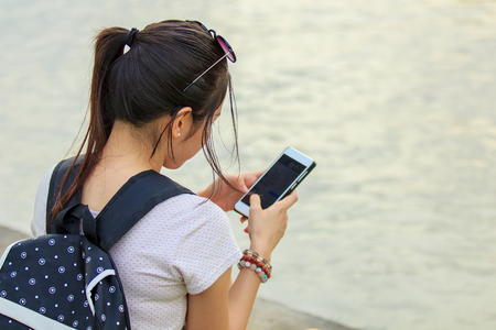 Asian young woman or girl use smart phone, with warm light on the evening.の写真素材