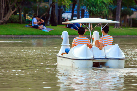Two lovers ride duck boat at the public park, with warm light on the evening.の写真素材
