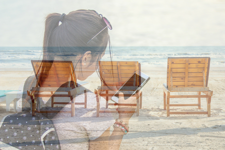 Double Exposure Image of Asian young woman or girl use smart phone with Bench or Seat on the beach of sea on the background.の写真素材