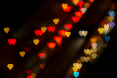 Bokeh of hearth shape of light from building or traffic road for valentine background.