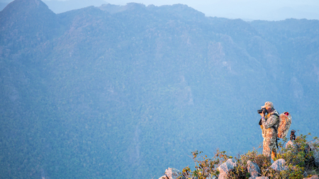 Photographer stand on the top of the rock stone mountain and other mountain on the background.の写真素材