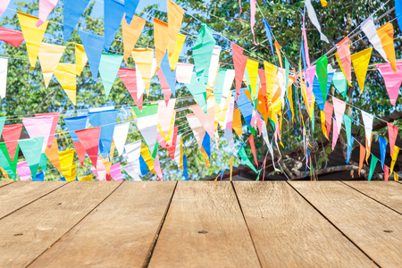 Empty wooden table or plank with colorful paper flag decoration at fair or celebration event on background for product display.の写真素材